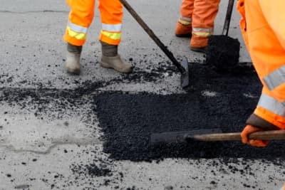 Worker repairing a pothole on a road